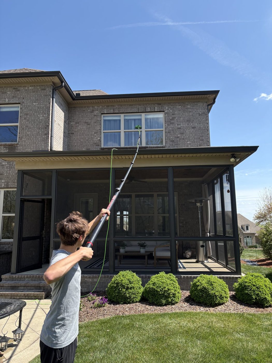Sunday technician cleaning a second-story window from the ground with a pure-water pole